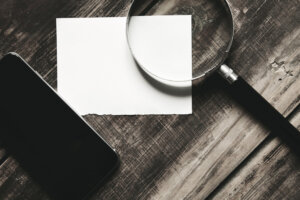 Lupa, papel e celular sobre mesa